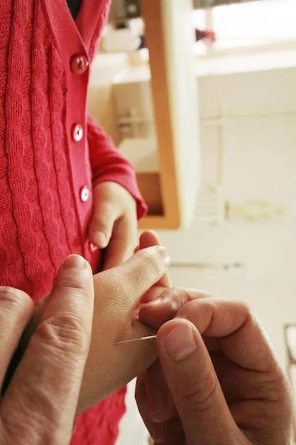 A child's eye view of a close-up of a parent's hands carefully sewing a tear in a stuffed animal. The animal is a well-loved teddy bear with slightly matted fur. The focus is on the delicate stitches and the care being taken to mend the toy.