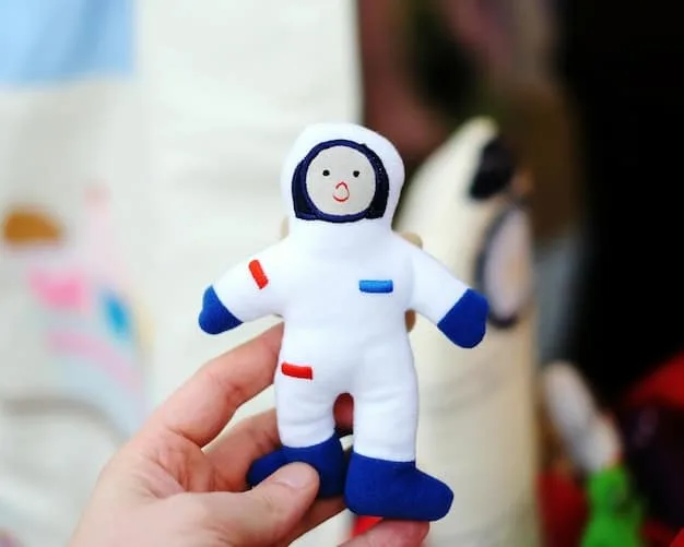 A close-up shot of a CPSC (Consumer Product Safety Commission) official inspecting a toy for potential safety hazards. The official is using a tool to measure small parts, and the background includes toys labeled with warning signs.