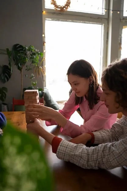 A child playing with wooden toys with an adult smiling and watching; light from a nearby window.