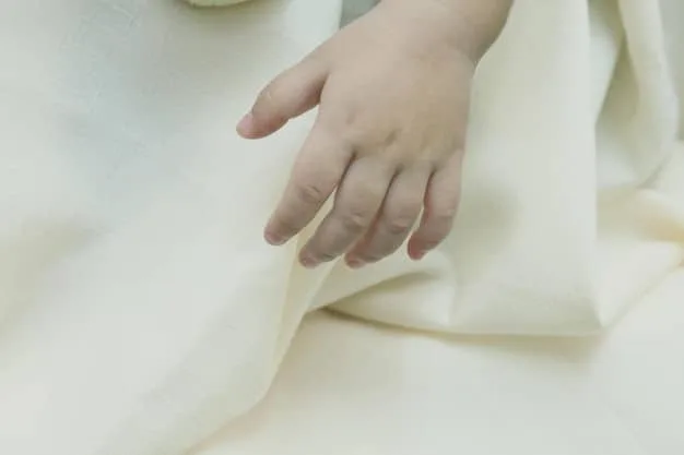 A close-up shot of a child's hand touching a soft, organic cotton t-shirt, highlighting the texture and quality of the fabric. The background is blurred to emphasize the material.
