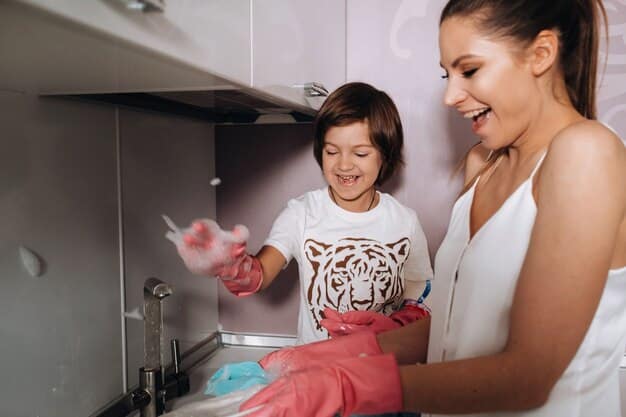Close-up of a mother cleaning a plastic toy with a damp cloth and soapy water. The background is a brightly lit kitchen sink with other toys waiting to be cleaned.
