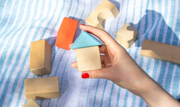 A close-up shot of a child's hands playing with a set of wooden building blocks on a playmat made from organic cotton. The blocks are various shapes and sizes, displaying the natural wood grain and edges. The colors are soft and muted to ensure they are made with non-toxic dyes. The focus is on the child's interaction with the toys, highlighting their tactile and educational value.