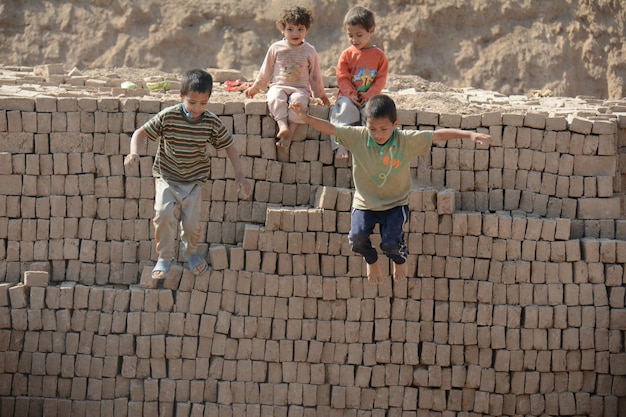A group of children are enthusiastically working together to build a large structure out of interlocking building blocks. The structure is colorful and complex, showcasing their collaborative engineering skills.