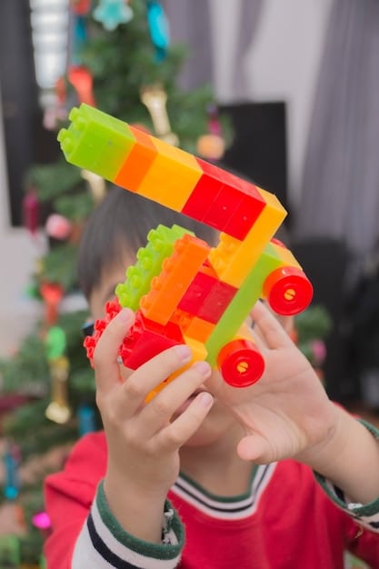 A close-up shot of a child's hands assembling a complex structure using a building block set, with different colored blocks scattered around. The child is focused and smiling slightly.